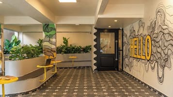 A hallway with a tiled floor, a reception desk, and a wall with a 'HELLO' mural.