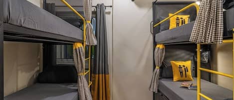 A compact room with bunk beds, a curtain, and an air conditioning unit.