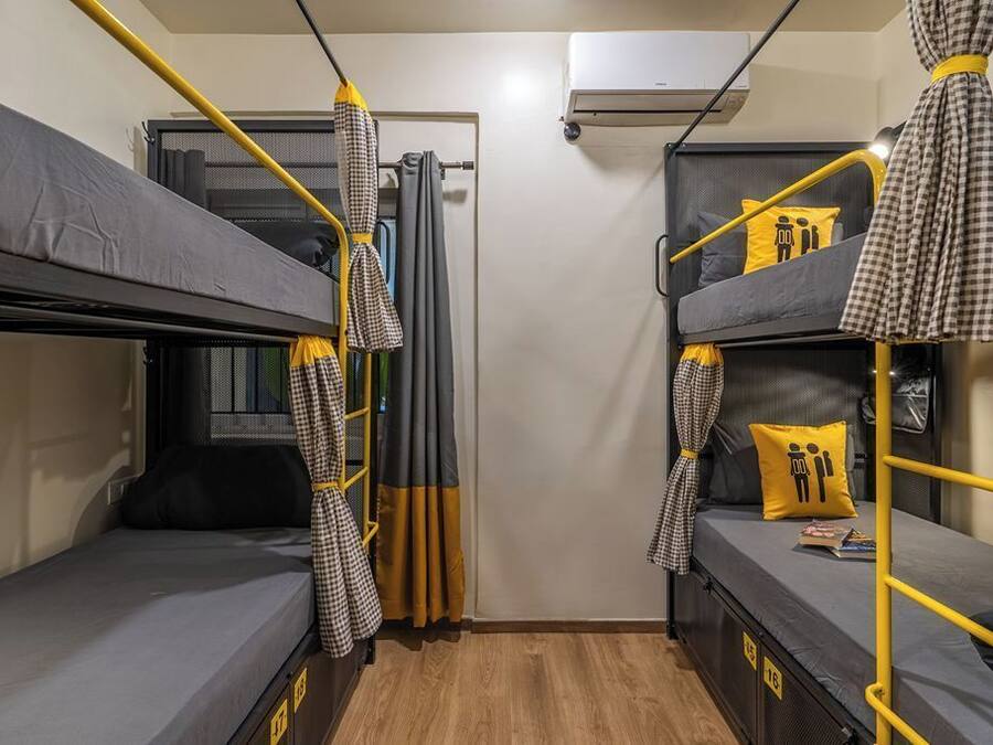 A compact room with bunk beds, a curtain, and an air conditioning unit.
