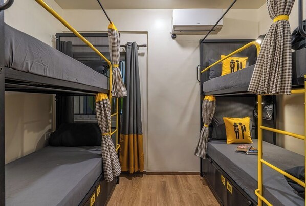 A compact room with bunk beds, a curtain, and an air conditioning unit. - The Hosteller Bangalore, CV Raman Nagar (Bengaluru)