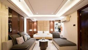 A modern hotel room with a large bed, two sofas, a coffee table, and built-in wooden paneling. - TOS Residency Jublee Hills By OTABoostup (Hyderabad)