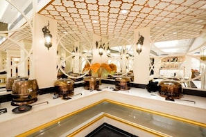 A luxurious interior with a geometric ceiling design, reflective surfaces, and modern lighting fixtures.