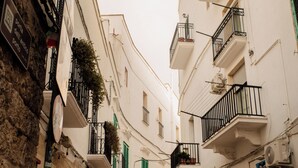 A narrow street with white buildings, balconies with black railings, and a sign indicating a historical port. - Dimora Rossella (Monopoli)