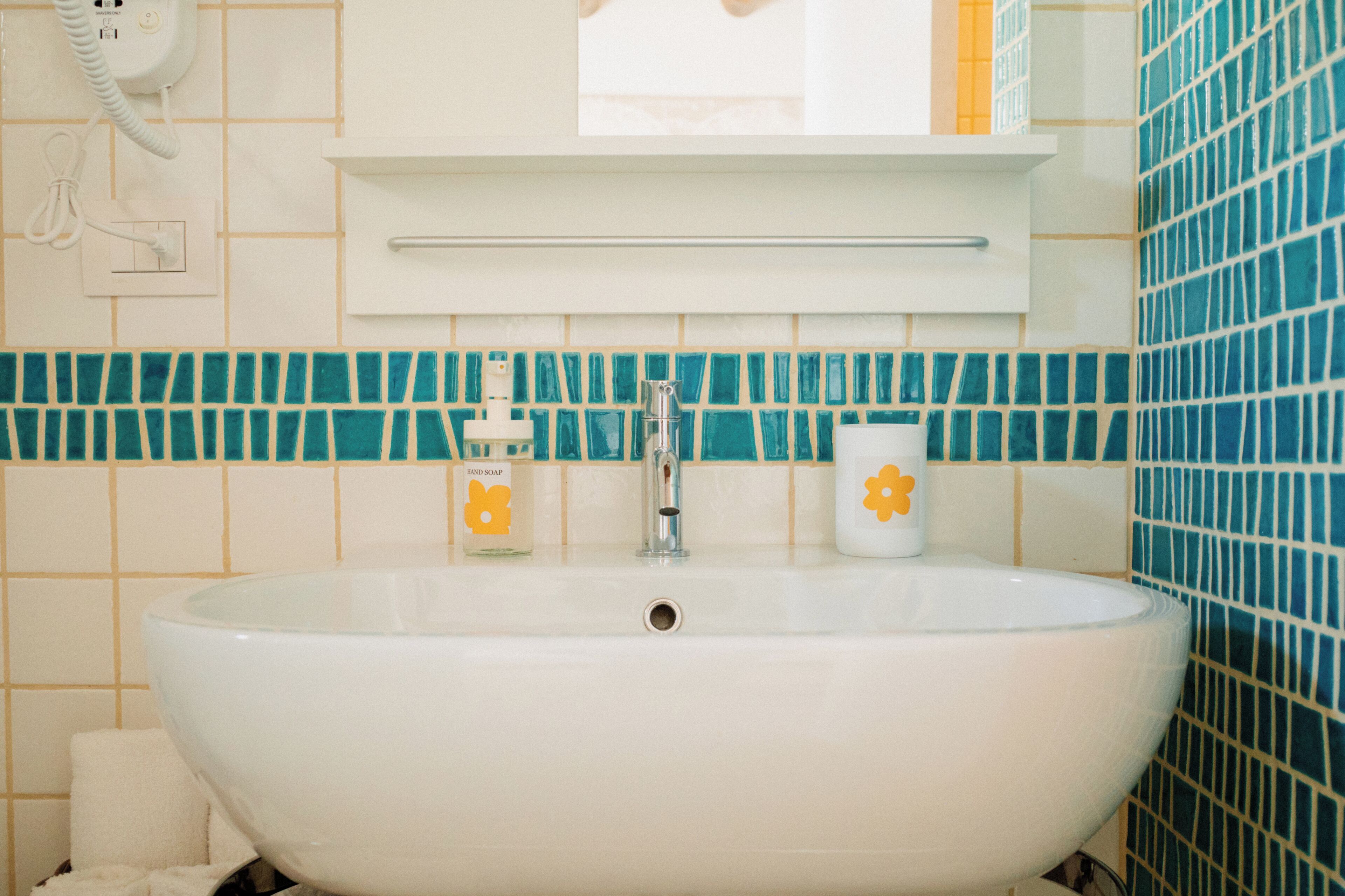 A bathroom with a white sink, a mirror above it, and a tiled backsplash.