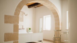 A bathroom with a white vanity, a mirror, a chair, and a window. - Dimora Rossella (Monopoli)