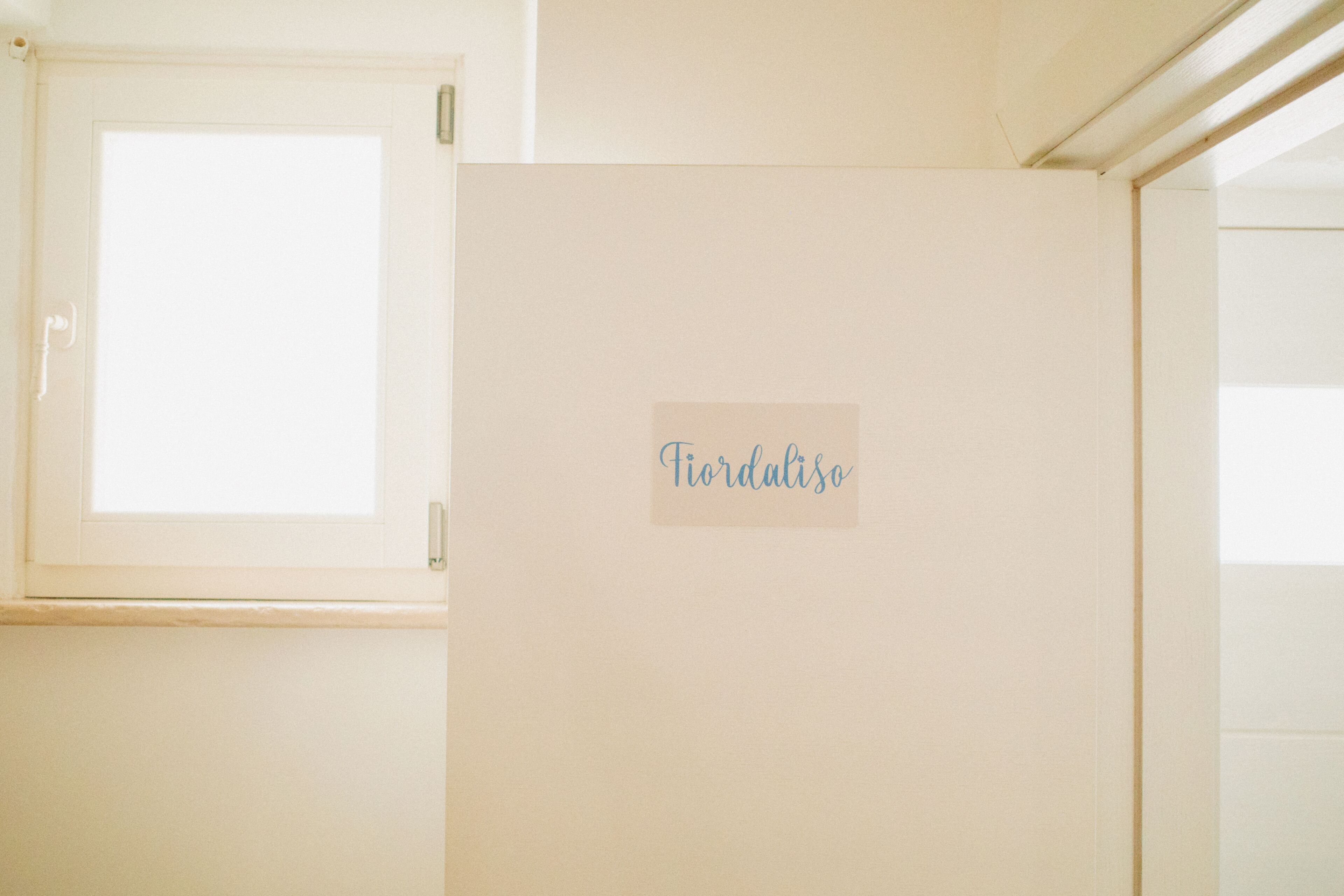 Habitació amb una porta que diu 'Fiordaliso', una finestra i un pom de porta.