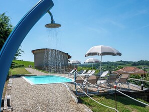 Ein Poolbereich mit Wasserspiel, Liegestühlen und Sonnenschirmen.