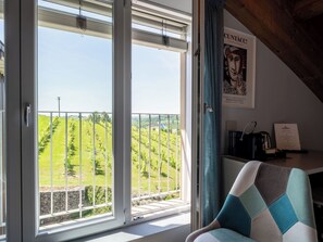 A room with a large window overlooking a vineyard, a chair, and a coffee machine on a table. - Guesthouse Dellavalle by Interhome (Vigliano d'Asti)
