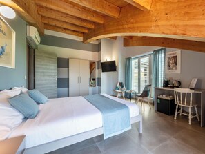 Ein Schlafzimmer mit Bett, Schreibtisch, Stühlen, Fernseher und einem Fenster mit Vorhängen.