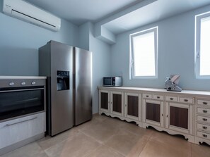 Una cucina moderna con forno integrato, frigorifero in acciaio inossidabile, dispenser d'acqua, forno a microonde e un pensile con cassetti.