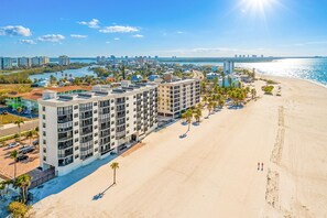 A beachfront hotel with multiple floors, a sandy beach, and a view of the ocean. - Beachfront 2B/2B Vacation Condo at Shamron Beach! Pool! Book Now For Dream Vacation! (Fort Myers Beach)