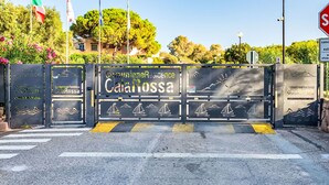 A gated entrance with 'Camunione Residence CalaRossa' signage, a stop sign, and a pedestrian crossing. - Lavanda 2301 Bis by Interhome (Isola Rossa)