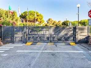 A gated entrance with 'Camunione Residence CalaRossa' signage, a stop sign, and a pedestrian crossing. - Lavanda 2301 Bis by Interhome (Isola Rossa)