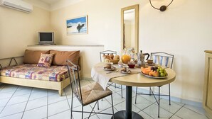 A room with a bed, a dining table with breakfast items, a TV, and a painting on the wall. - Lavanda 2301 Bis by Interhome (Isola Rossa)