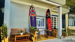 A covered outdoor area with benches, potted plants, and two surfboards mounted on the wall. - LŨA XÓM CHÀI là một homestay nằm ở làng chài Trần Phú, Dương Đông, Phú Quốc (Đặc khu Phú Quốc)