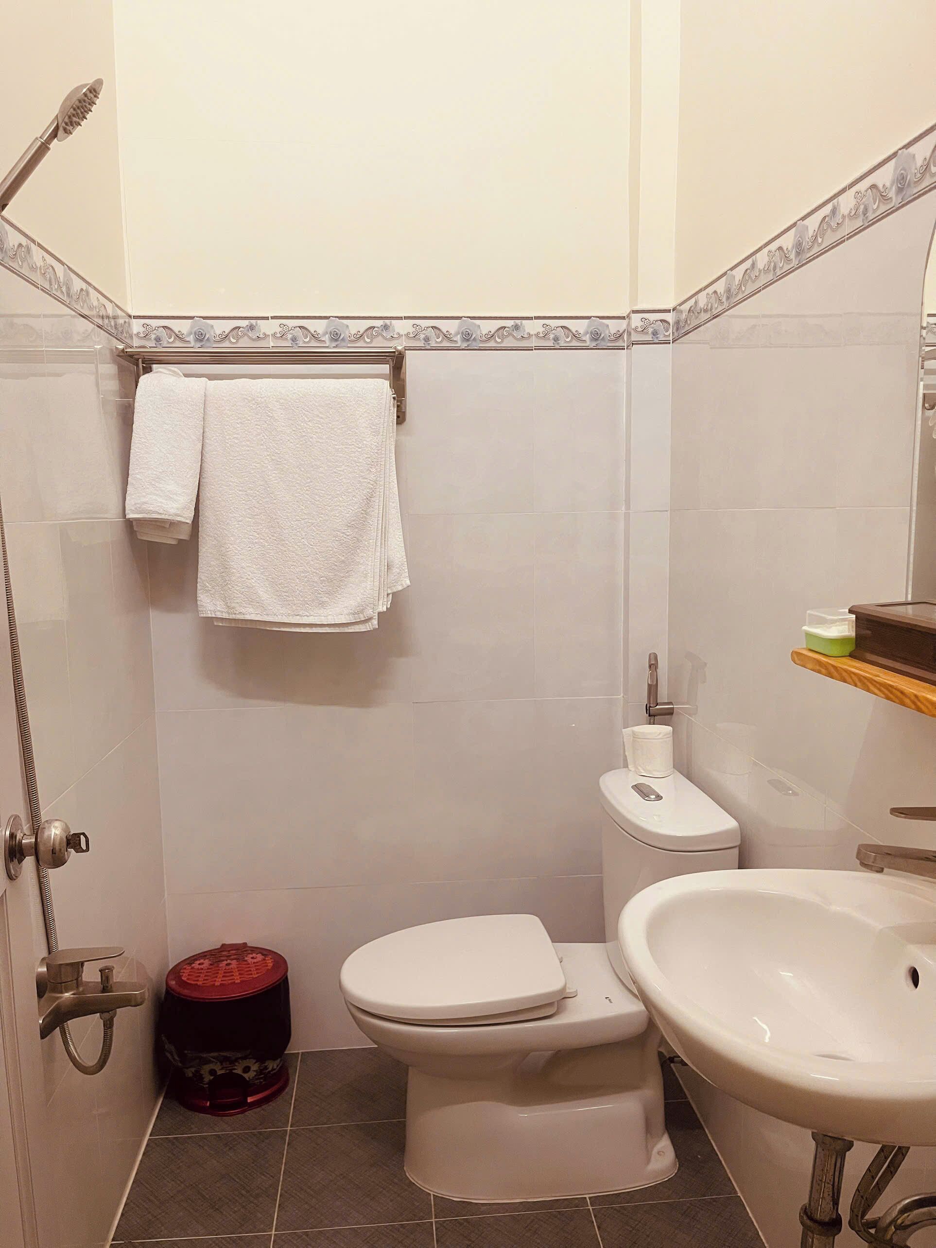 A bathroom with a toilet, sink, shower, and a towel rack.