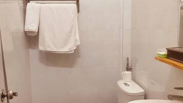 A bathroom with a toilet, sink, shower, and a towel rack.