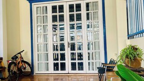 A room with a large sliding glass door, a bicycle, and a potted plant. - LŨA XÓM CHÀI là một homestay nằm ở làng chài Trần Phú, Dương Đông, Phú Quốc (Đặc khu Phú Quốc)