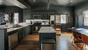 A modern kitchen with dark cabinetry, stainless steel appliances, and a marble backsplash. - The Reserve at 151 (Afton)