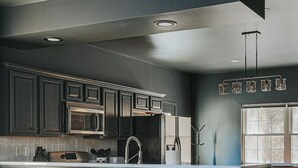 A modern kitchen with dark cabinetry, stainless steel appliances, and a central island. - The Reserve at 151 (Afton)