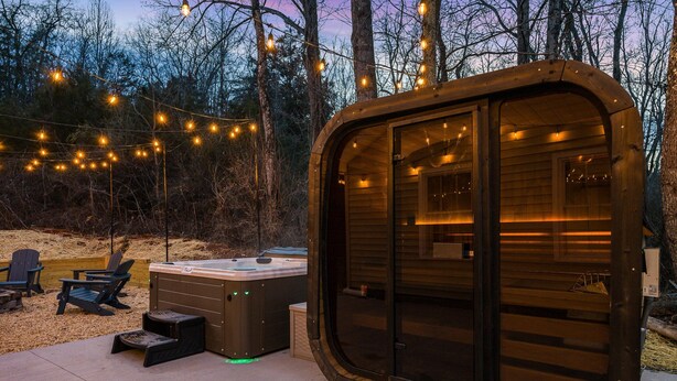 A wooden cabin with a sliding door, a hot tub, and string lights. - The Reserve at 151 (Afton)