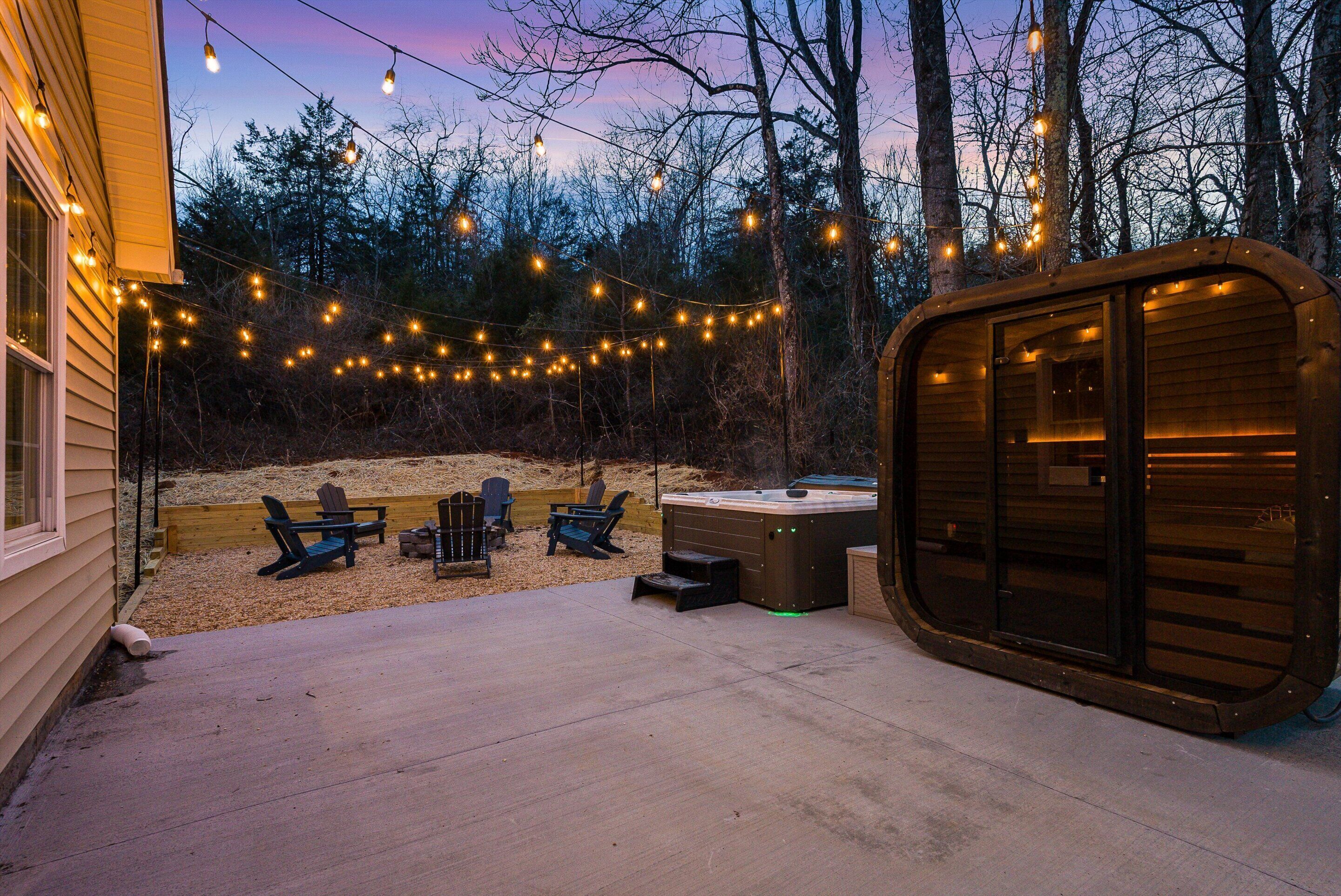 Une terrasse en bois agrémentée de guirlandes lumineuses, un jacuzzi et des sièges d’extérieur.