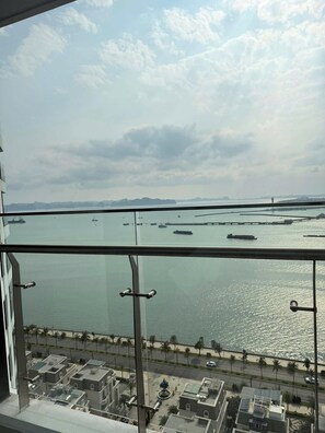 A view from a high-rise window overlooking a body of water with boats, a distant island, and a bridge. - Saphire Ha Long Luxury apart (Ha Long)