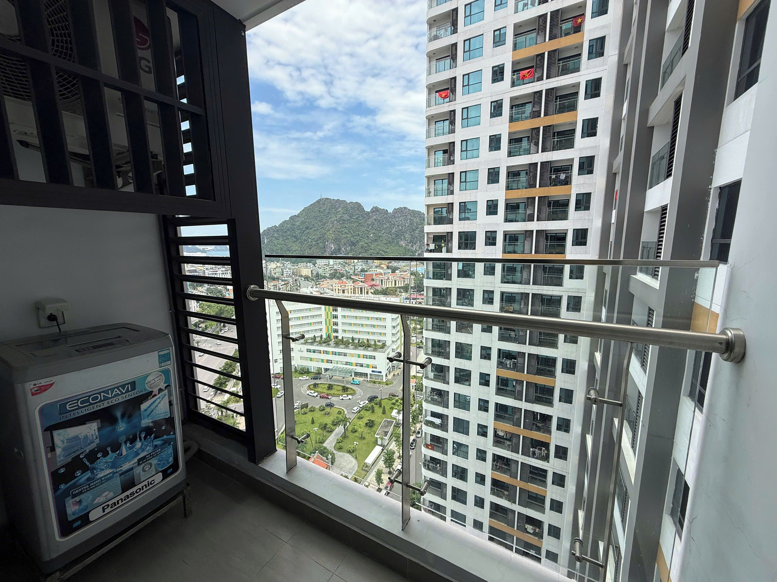 A high-rise building with multiple balconies, a clear view of the cityscape, and a Panasonic device on a shelf.