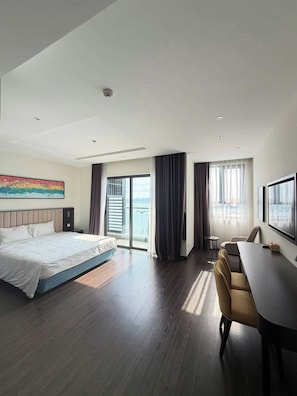 A modern hotel room with a large bed, a desk, and a view of the outdoors. - Saphire Ha Long Luxury apart (Ha Long)