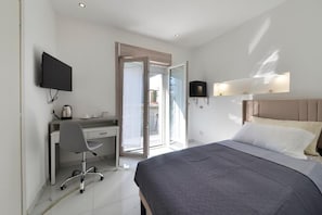 A modern hotel room with a bed, desk, chair, TV, and a sliding door to a balcony. - GIOIA E RELAX DI ZR  (Rho)