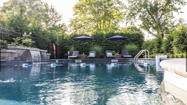 A swimming pool with lounge chairs, a waterfall feature, and umbrellas.