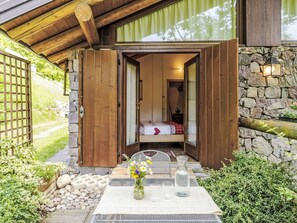 Una stanza accogliente con un letto, un tavolo con un vaso di fiori e un muro in pietra.