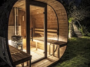 Uma cabana circular de madeira com porta de vidro, um banco e uma mesa pequena.