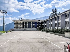 A building with a courtyard, large windows, and a mountain in the background. - Ciasina Alpina by Interhome (Folgarida)