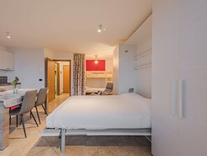 Une chambre d’hôtel moderne avec un lit, un bureau avec des chaises, un mur d’accent rouge et un lit superposé.