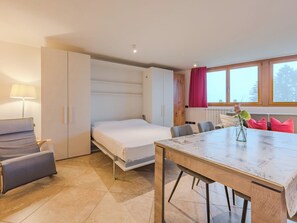 A compact room with a bed, a dining table, and a window with curtains. - Ciasina Alpina by Interhome (Folgarida)