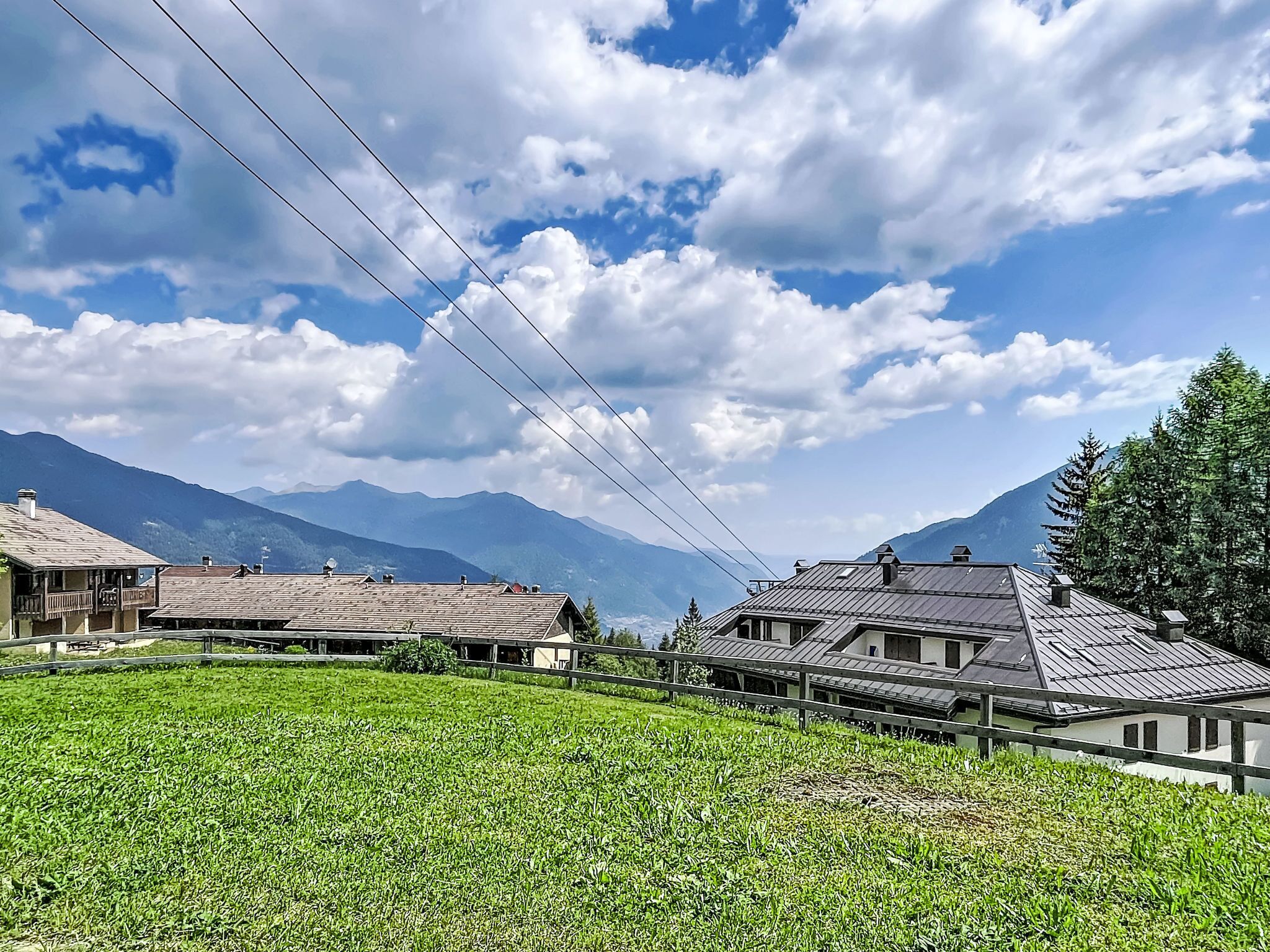 Un paysage rural avec des maisons, un champ et des montagnes en arrière-plan.