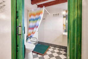 A bathroom with a toilet, shower, and a checkered floor.