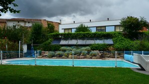 En swimmingpool omgiven av ett staket, med en byggnad i bakgrunden.