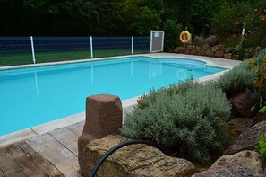 Una piscina con cerca azul, una reja y follaje circundante.