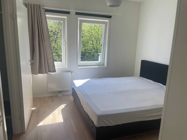 A bedroom with a bed, two windows, a radiator, and a door. - 3 Bedroom new Flat Close to Oslo Fjord (Bærum)