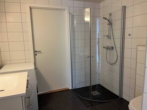 A bathroom with a glass-enclosed shower, white tiled walls, and a white sink. - 3 Bedroom new Flat Close to Oslo Fjord (Bærum)