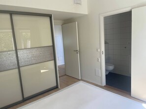 A room with a sliding door, a white toilet, and a tiled wall. - 3 Bedroom new Flat Close to Oslo Fjord (Bærum)