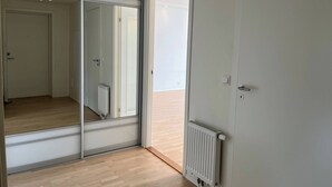 Et værelse med en skydedør, en radiator og trægulv.