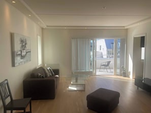 A modern living room with a sofa, ottoman, and glass coffee table. - 3 Bedroom new Flat Close to Oslo Fjord (Bærum)