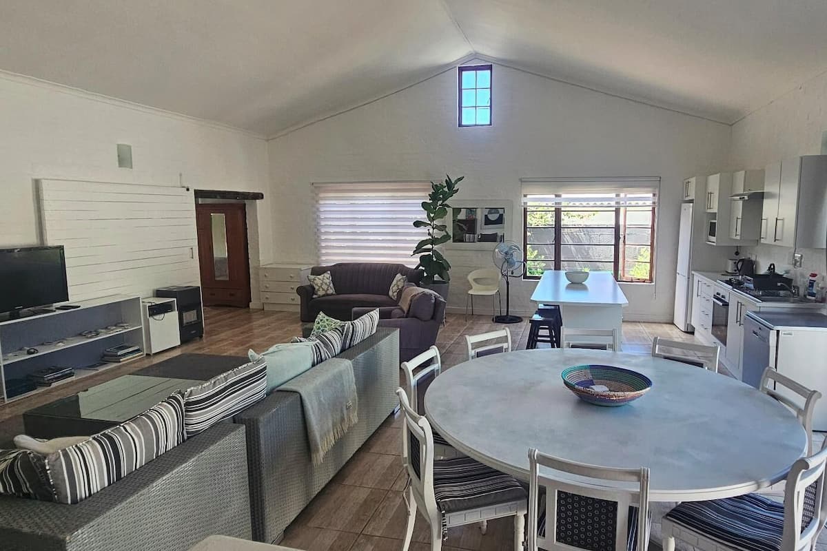 Una sala de estar moderna con televisor, sofá, mesa de comedor y zona de cocina.