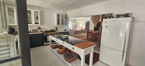 A modern kitchen with white cabinets, a central island, and a refrigerator. - The Lily House Hermanus (Hermanus)