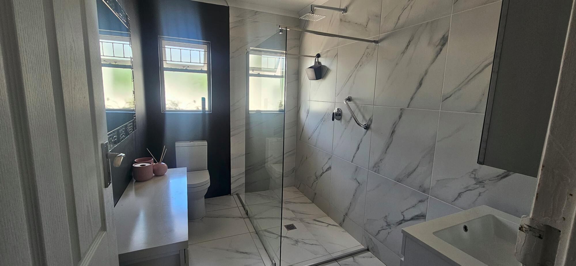 A bathroom with a glass-enclosed shower, a toilet, and a sink with a countertop.