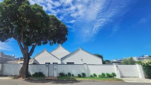 Una casa moderna de dos pisos amb façana blanca, un garatge i un arbre al primer pla.
