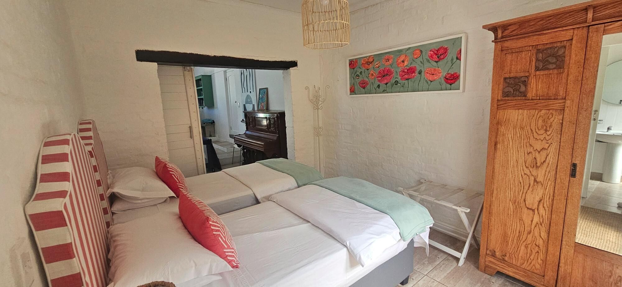 Un dormitorio con cama, armario de madera, un cuadro y espejo.